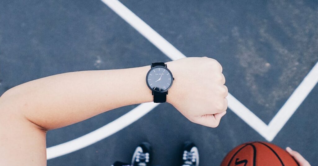 A basketball player checks their wristwatch while holding a ball on an outdoor court.