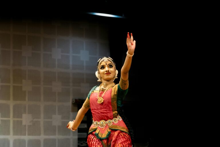 A Bharatanatyam dancer in traditional attire gracefully performing a classical Indian dance on stage.